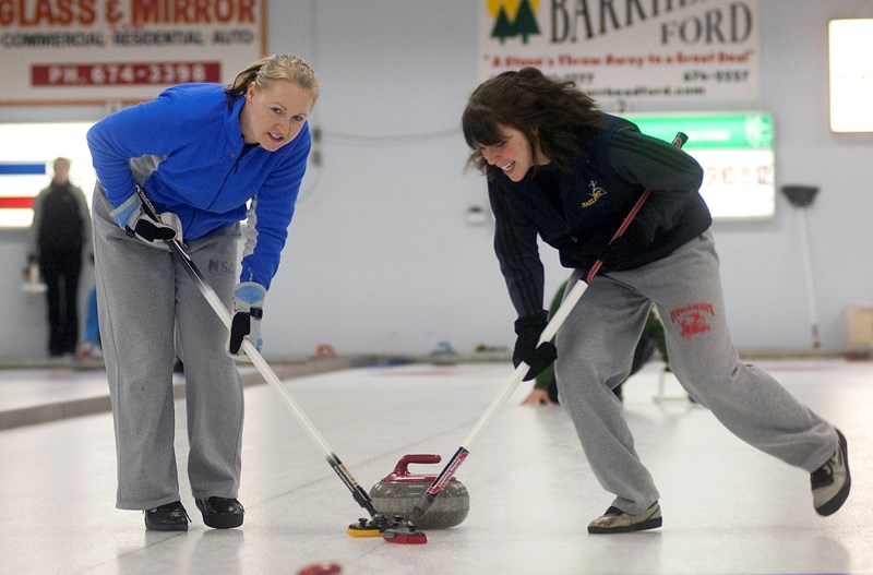 Sisters Sandy Holowaychuk (left) and Kelsey Mccracken, members of the winning team, sweep hard during the A final game of Barrhead &#8216;s 2013 Ladies Bonspiel Jan. 19.