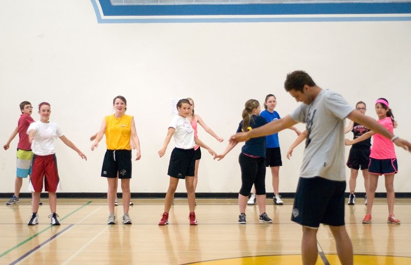 Jordan Teo, a student and basketball player at Grande Prairie College, leads a group of students through a warm up exercise before they begin the day.