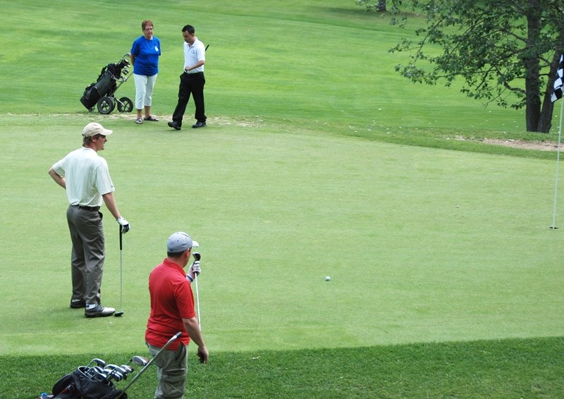 Tyler Chapman (centre left) gets ready to sink a 12 foot birdie putt on the difficult 7th hole at Devon during the Alberta Special Olympics.