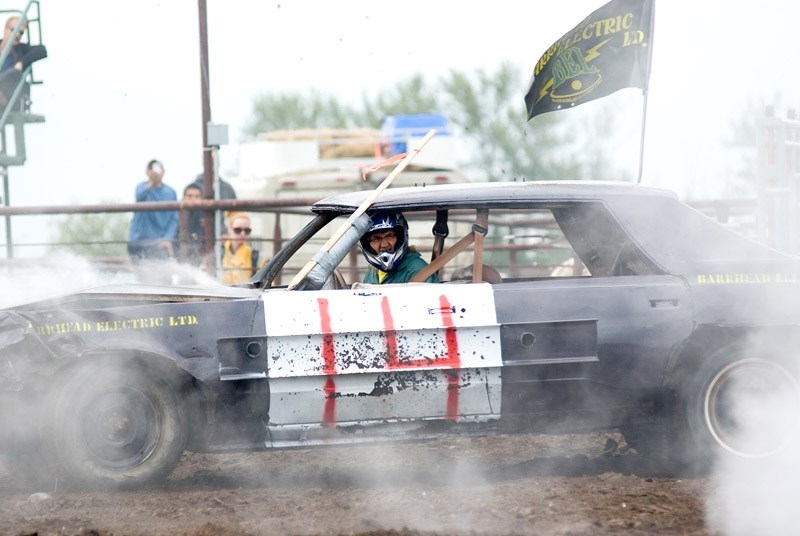 Demolition derby event organizer Greg Petruchik squints through the smokey air to see his opponents during the first of two car heats. Petruchik placed second in each heat,