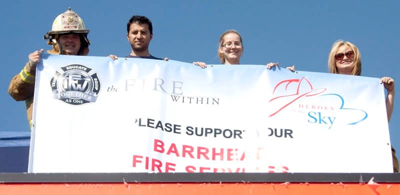 Rooftop campers: Pictured, left to right, are Deputy Fire Chief Gary Hove, Capt. Ty Assaf, and firefighters Sam Beeston and Jacquie Bradet. They display a banner calling for