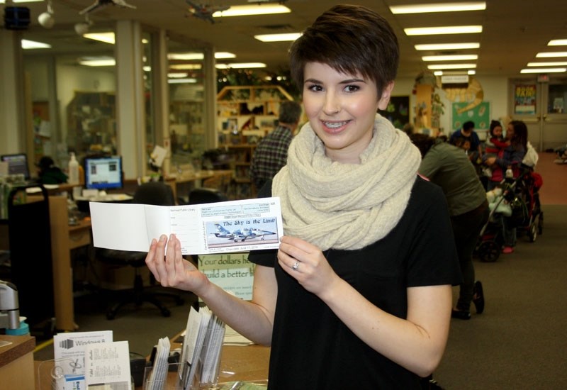 Barrhead Public Library &#8216;s CAP intern Veronica Dumonceau displays a book of &#8220;The Sky is the Limit &#8221; tickets. The raffle winner will fly on a fighter jet.