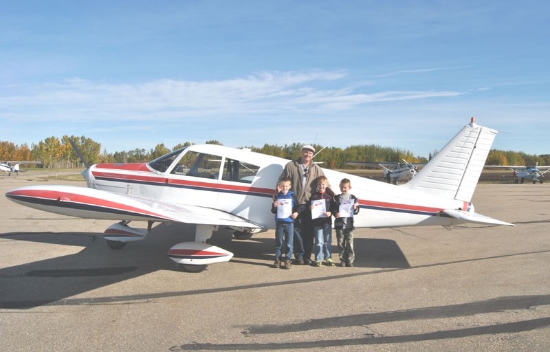 COPA Flight 185 president, John Burrows, presents Adam Van Bostelen, 9, Mathew Chinn, 8 and Ryan Van Bostelen, 8, with their COPA For Kids certificates.