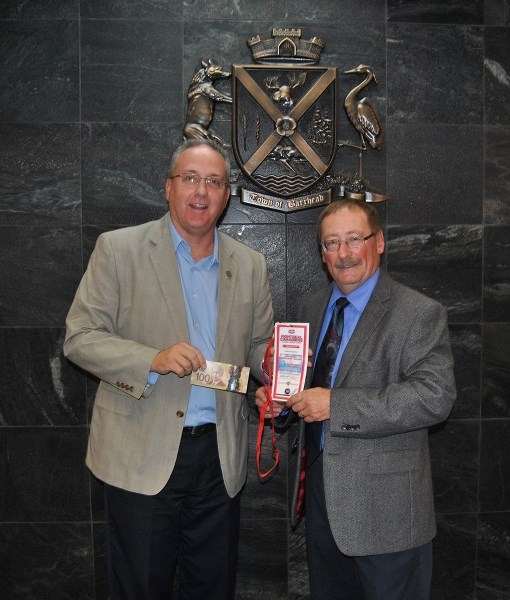 Barrhead Chief Administrative Officer Martin Taylor (l) sells Barrhead Mayor Gerry St. Pierre the first ticket for upcoming Montreal Canadiens Alumni before the start of the