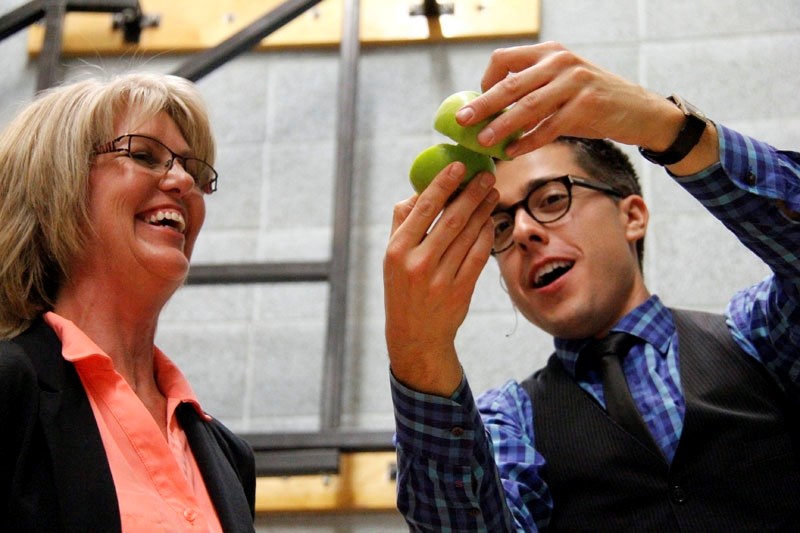 Judy Kummer is amazed to see the card she had just torn up in the apple as she participates in a magic act performed by Sheldon Casavant, a magician brought to Oktoberfest to 