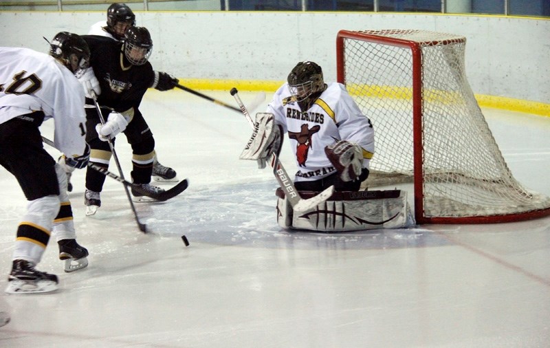 Ducks player attempts to score against Renegades goalie, Dawson Fischer, with fellow teammate Aedan Card helping stop the puck.