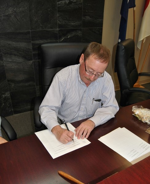 Barrhead Mayor Gerry St. Pierre signs the pool agreement after town council officially ratified it during a special meeting on Tuesday, Dec. 16.