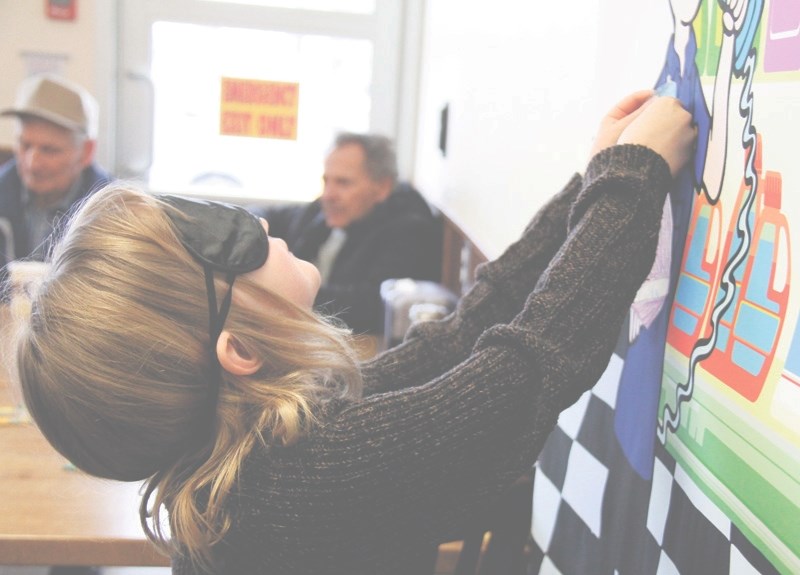 Lyla MacKinnon, 6, takes a shot at pin the tie on the grocery guy during the grand re-opening of Freson Bros. on Saturday, March 21. The celebration was hosted as a way of