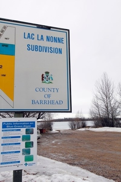 A sign maps out a subdivision along Lac La Nonne, with a smaller sign providing information for the public on blue-green algae.