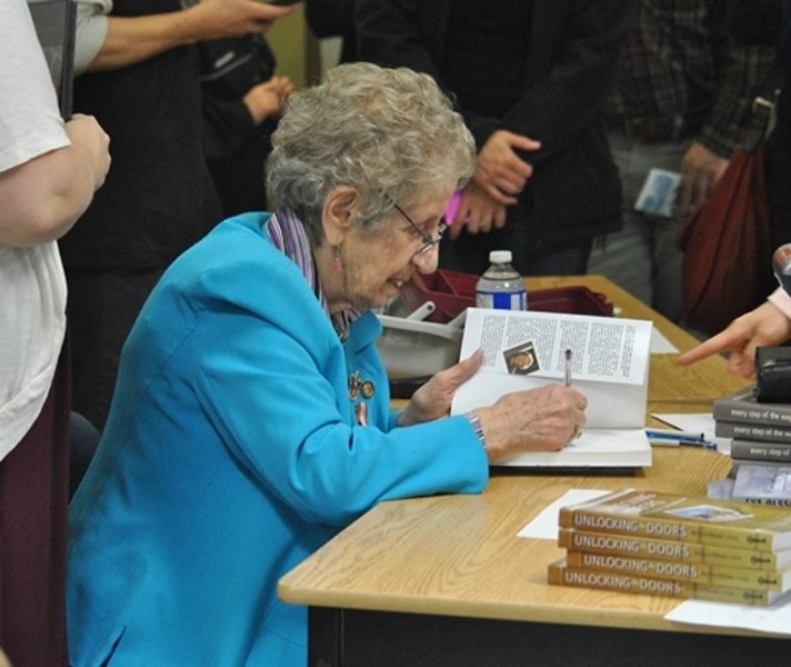 Dr. Eva Olsson autographs one of her three best selling books, Unlocking the Doors: A Woman &#8216;s Struggle Against Intolerance, Remembering Forvever: A Journey of Darkness 