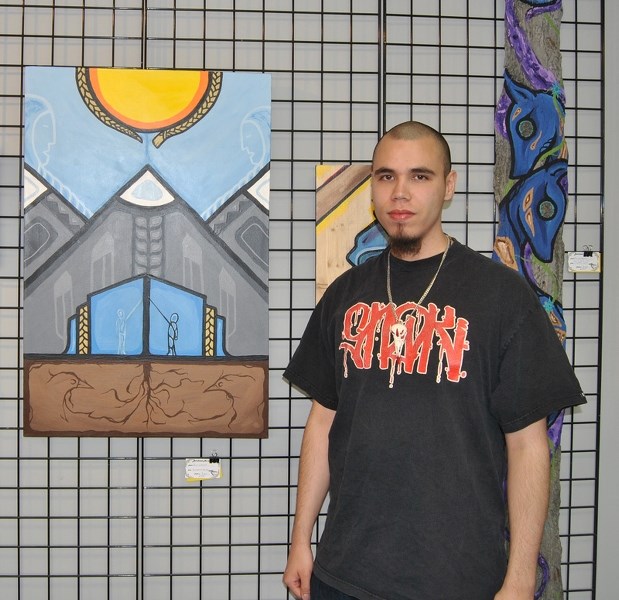Travis Ladouceur stands beside a painting called Sundance For You. It is a painting he did to honour his brother who recently passed away.