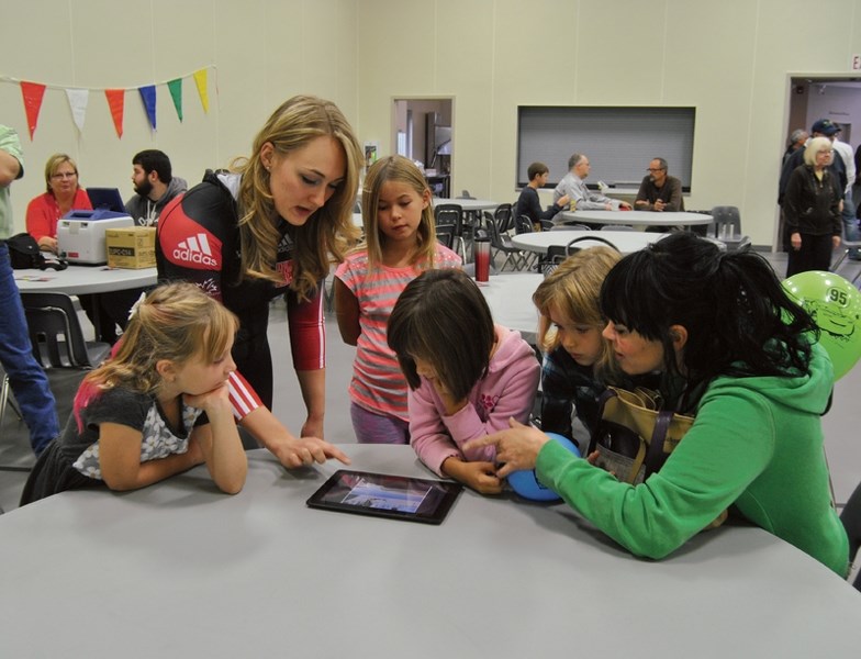 From left: Lyla Mackinnon, Melissa Lotholz, Emily Moen, Emilea Brinkworth, Alivea Brinkworth and Nicole Brinkworth. Lotholz shows a group of people a slide show from one of