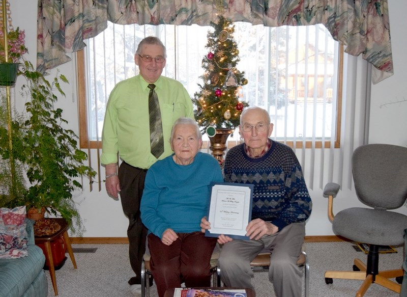 Barrhead town Coun. Roy Ulmer (l) presents a certificate of congratulations to Betty (m) and Werner for their 65 years of marriage.