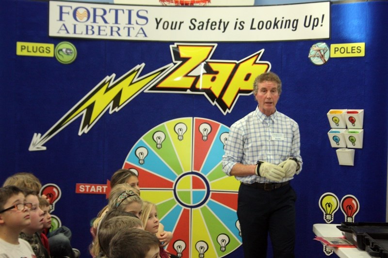 Putting on a pair of insulated gloves, one of the safety education coordinators that presented ZAP in conjunction with Fortis Alberta, Keith Smith, prepares to show kids a