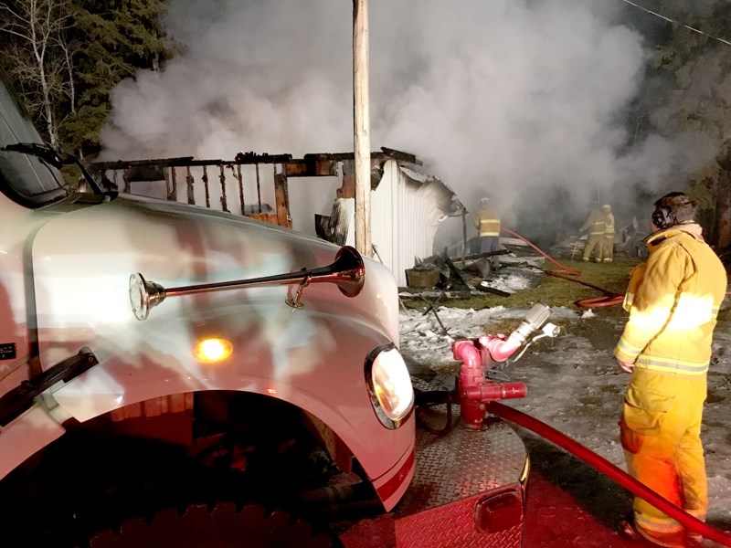 A member of the Barrhead Fire Department keeps an eye on his colleagues who fought an electrical-short related fire at a residence on Range Road 40 during the night of