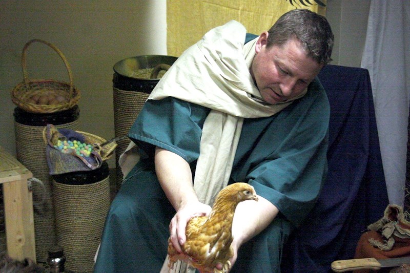 Jeff Schmidt, acting as a greeter for the town of Jerusalem, offers his guests a chicken and some colourful eggs, at the first station of Bethel &#8216;s Walk With Jesus, on