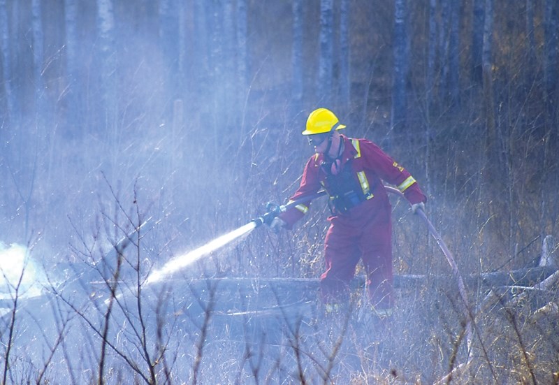 A member of the Busby Fire Department extinguishes one of the many spot fires which broke out near the Willow Wilde Cemetery on April 2.