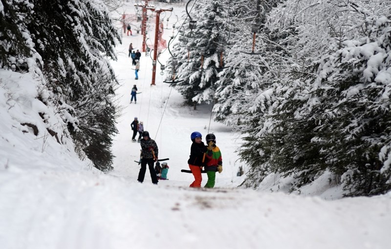 A group of young skiers and snowboarders go up the T-bar during a busy Saturday afternoon.