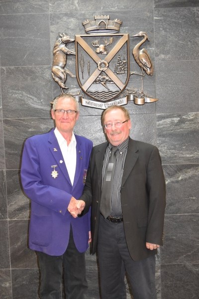 Bruce McLean (l), Barrhead Elks president and mayor Gerry St. Pierre shake hands after council unanimously accepted the Elks donation of $100,000 to the Barrhead and District 