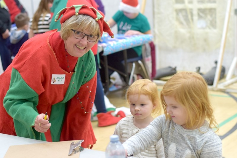 Mama Elf (l) (Anita Sherwood) helps Evangeline (m) 2, and Ava Coleman pay for their presents.