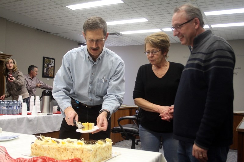 Mark Oberg (l) handing out pieces of cake to his former co-workers Linda West (m) and Rick Neuman.
