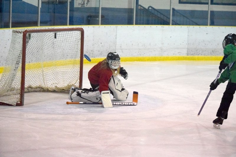 Goaltender Emily Hodgetts gets enough of a shot to deflect it wide of the net.