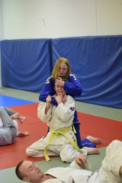 Jessalyn Helmus (behind) takes advantage of her superior position by using a choking technique on Harold Helmus.