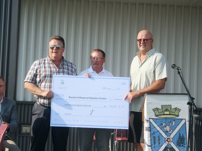 County of Barrhead reeve Doug Drozd and Town of Barrhead mayor Gerry St. Pierre accept a donation from the Agrena Society president Shannon Carlson.