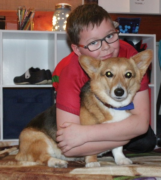 Kahlin Chartier hugs his friend Quinn the therapy dog following a session at Westlock Elementary School &#038; Feb. 14. Every Wednesday, Quinn and another therapy dog spend