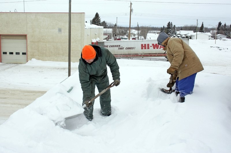 Travis and Trevor Luchka clear snow off the Westlock News building roof Friday morning. With the weather now getting warmer, the snow will become heavier and the possibility