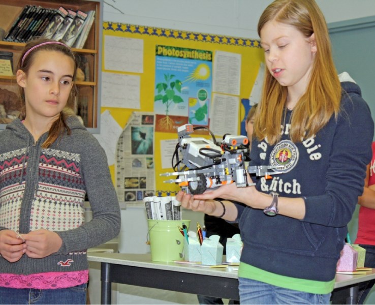 Hanna Nakonechny holds her team&#8217;s robot, Tribot, while Carli DeKoch looks on. The girls are members of Margaret Benham&#8217;s robotics club and were showcasing their