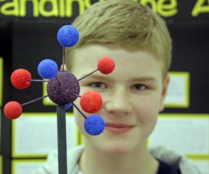 Aaron Friesen peers through a model of an atom, which was a visual aid for his science project, &#8220;Nuclear Energy &#8211; Understanding the Atom. &#8221; Students from