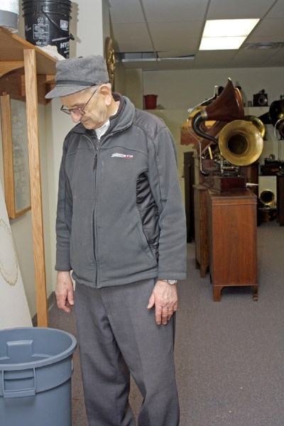 Historical society president Steve Chodan looks into a garbage can set up to collect water dripping from the ceiling in the Pioneer Museum. The leaking roof is threatening