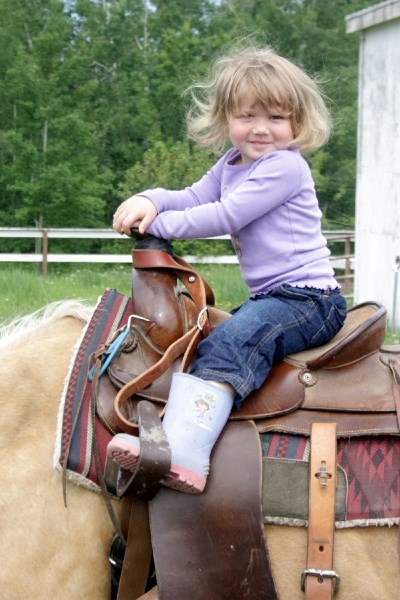 Tamika Seipert, 3, sits atop her trusty steed before the gymkhana last Saturday during Busby Farmers&#8217; Days.