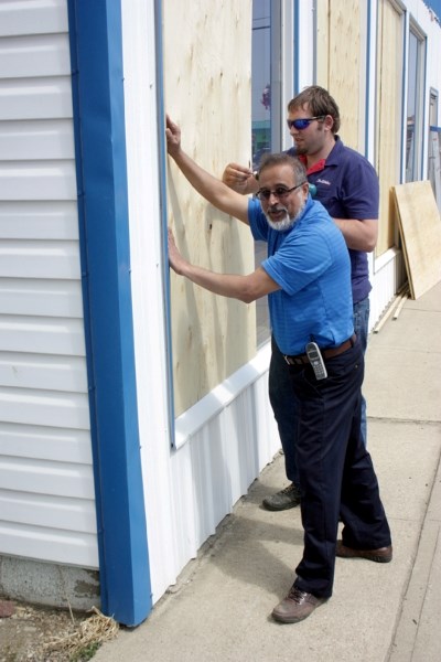 Ali Jamaly (left) and Mike Kostiw board up the windows at the True Balue Hardware in Westlock after vandalism and a break-in last week. Jamaly said the incidents have him