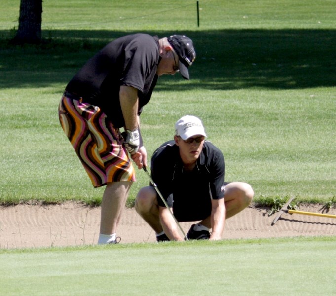 Blind golfer Brian MacLeod receives assistance from his caddy Brian Smith to line up a shot during a warm-up round before the July 26-27 Western Canadian Blind Golf