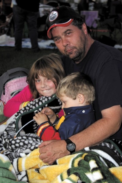 Ed Fauque shares a blanket with his kids Mackenzie and Nicholas at the Movie in the Park event at Keller Field last Saturday night.