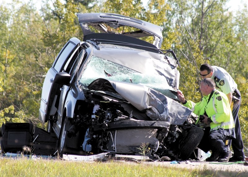 Westlock RCMP Cpl. Dave Casey and Const. Bob Archer, the RCMP&#8217;s collision reconstructionist, inspect the damage to the minivan.