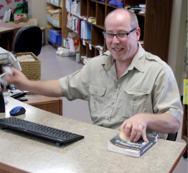 Librarian Doug Whistance-Smith checks a book out at the Westlock Municipal Library. Clyde residents could find it tougher to use the library&#8217;s services unless the