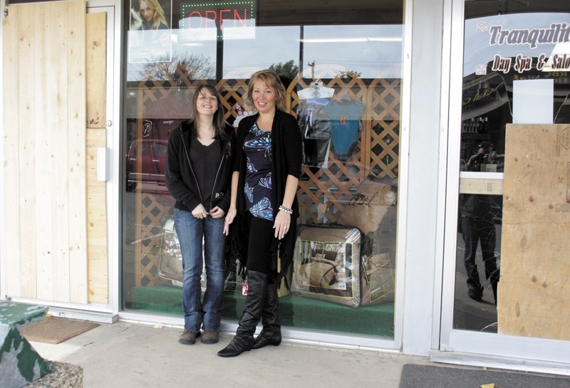 Outback owner Tanya Ehmler (left) and Tranquility Salon owner Carey Dzivinski outside their stores&#8217; boarded-up windows last Thursday morning. Thieves broke into seven
