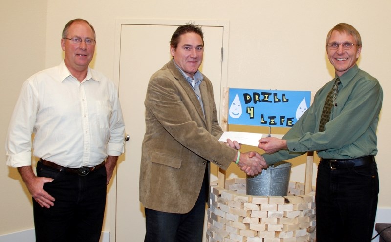 Patro Ken Stange (right) of the Cedar Christian Fellowship presents money raised during a 2009 Water 4 Life fundraiser to Dave McElhinney and Dave Nelson (left) for their