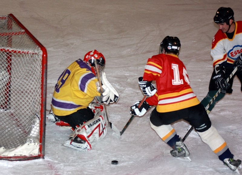 Craig Andrusiak (centre) tries to slip one past goalie Jordan Brand while John Foster moves in to help defend during the final Jubilee Arena ice time on March 22.