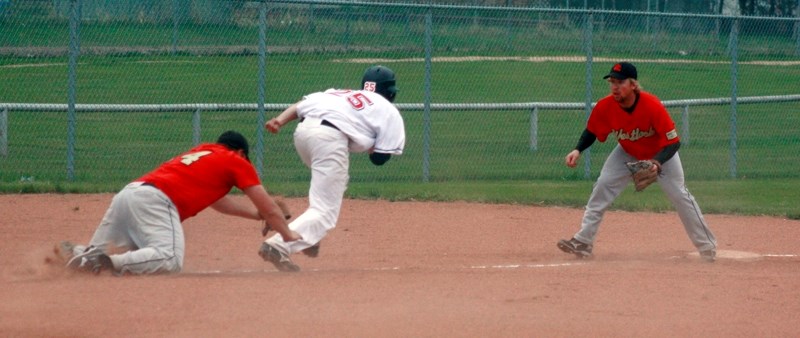 Westlock Red Lions third baseman Jordan Brand (right) watches as pitcher Adam Sawatzky dives to tag a Legal Indians runner on his way back to third base. The play ended the