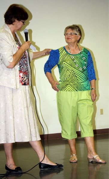 Olga Romanchuk (right) models an outfit while Susan Adam explains how it can be accessorized at the Trade Show for Seniors on June 15.