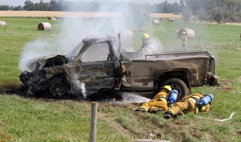 Barrhead firefighters work to extinguish the fire that engulfed one pickup truck involved in a serious collision on Aug. 22 at the corner of Township Road 610 and Range Road