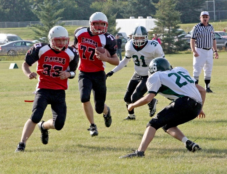 With some blocking help from Chase Boyson (33), the Westlock T-Birds’ Brian Vader (77) looks for an opening against the Athabasca Pacers in both teams’ season-opening game