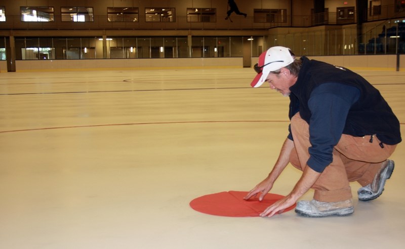 Brian Hennessey, a facility operator at the Westlock Rotary Spirit Centre, lays down one of the face-off dots in the new arena. Hennessey and several other works have been
