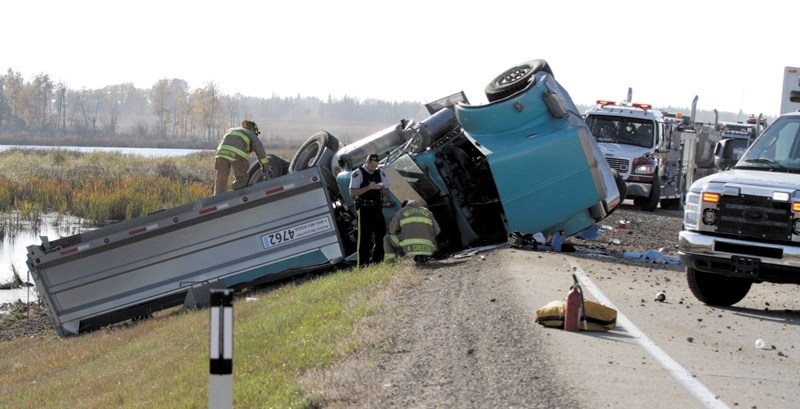 Westlock RCMP and firefighters examine a truck and trailer that went off Highway 18 east of Clyde on Thursday afternoon. Police report that the driver suffered serious