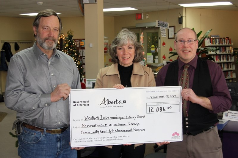 Westlock County councillor Bert Seatter (left) and librarian Doug Whistance-Smith (right) accept a $12,086 cheque from MLA Maureen Kubinec for renovations to the Fawcett