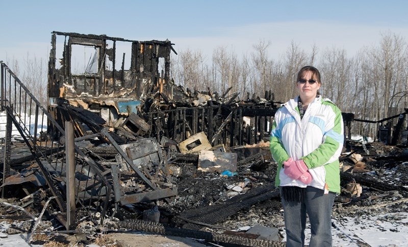 Pam Grenier, daughter of Edna and Lenard Jennings, stands beside what’s left of her parents’ house after it burned down Feb. 13.